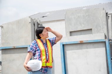 İnşaat mühendisi Asyalı kadın miğfer ve güvenlik yeleği olan mimar ya da mühendis bina ya da şantiyede çalışmaktan mutlu.