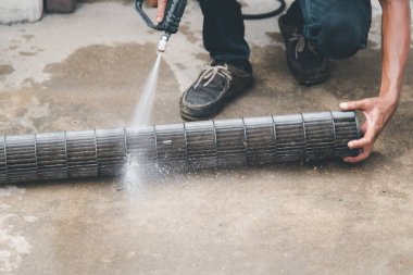 Bakım hizmeti sırasında müşteri evindeki duvardaki tozu temizlemek için havalandırma soğutucusunu suyla temizleyen işçiden işçiye.