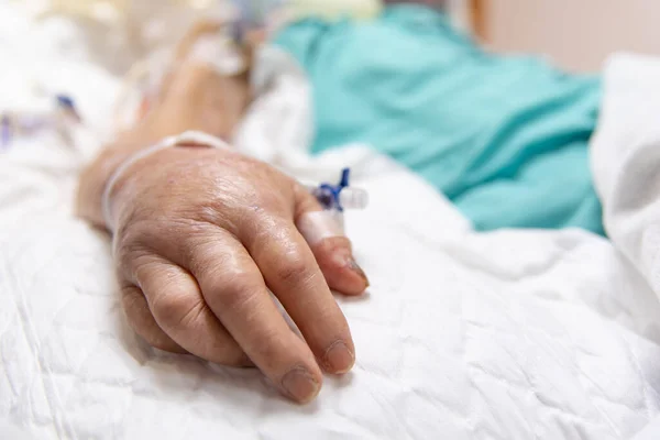 80歳以上のアジア系高齢女性80歳以上のインフルエンザ コビド19は 集中治療室 Icu に入院パッドと高齢患者の手で患者のベッドで 病院のコンセプトヘルスケア室で — ストック写真