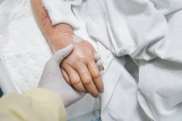 生理食塩水の点滴で入院中の患者と親戚患者手高齢者患者の手を握って — ストック写真