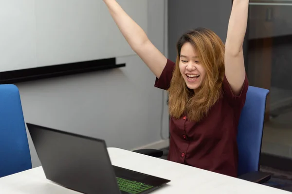 Asian woman is student, businesswoman working by computer notebook, laptop in office meeting room with whiteboard in background with happy and relax emotion in concept working woman, success in life