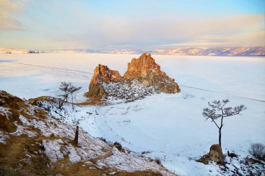 Kışın Olkhon Adası 'ndaki Burhan Burnu ya da Şamanka kayası manzarası. Donmuş Baykal Gölü, buzun üstünde kar.. 