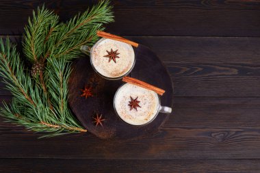 Koyu ahşap arka planda geleneksel kış yumurtalı likörü. Sütle iç, rendelenmiş hindistan cevizi, çırpılmış yumurta, Noel ve kış tatillerinde tarçın. Üst görünüm.