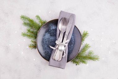 Noel sofrası. Kaliteli tabak, gümüş çatal bıçak, köknar dalları, açık gri arka planda şenlikli dekor. Noel yemeğine hazırlanıyorum.. 