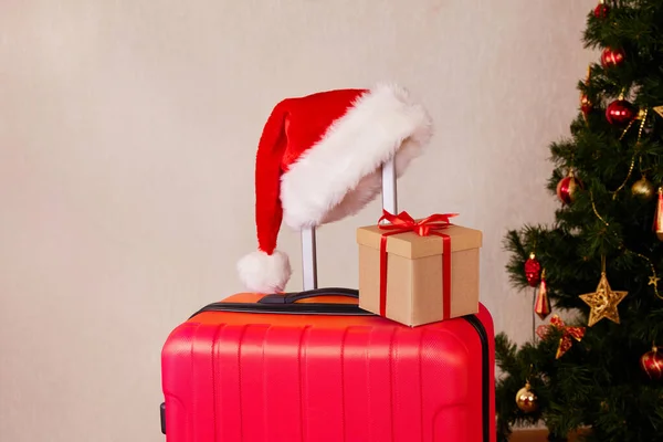 Kırmızı bir bavul, Noel Baba şapkası ve hediye kutusu. Noel için seyahat konsepti. 