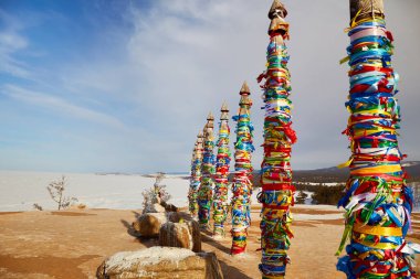 Kışın Baykal Gölü. Olkhon Adası. Burhan Burhan Burnu veya Şamanka Kayası 'nda renkli kurdeleli ahşap ayin sütunları. 