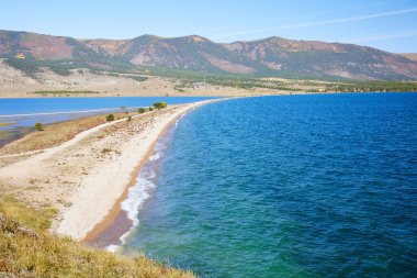 Sonbaharda Baykal Gölü. Cape Uyuga 'dan körfezin manzarası. Güzel manzara: Turkuaz su, kamp alanları ve Kurma köyündeki evler. 