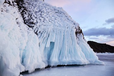Icy rocks of Oltrek Island in winter. Frozen Lake Baikal at sunset. 