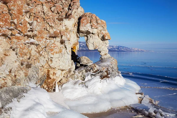 A happy girl travels on Lake Baikal in winter. Beautiful winter landscape, arch in the rock in the shape of a heart. — Photo