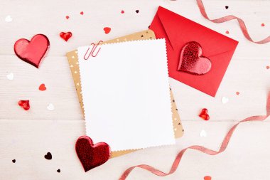 Sevgililer Günü geçmişi. Boş tebrik kartı, ilan-ı aşk, zarf, kırmızı kurdele, dekor, beyaz ahşap arka planda kalpler. Sevgililer Günü konsepti. 