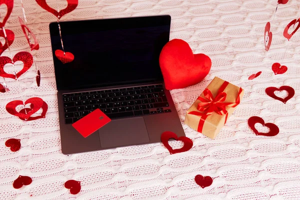 stock image Laptop, credit card, gift, decor, hearts on a white knitted blanket. Shopping online for Valentines Day.