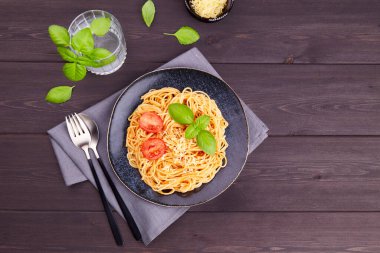 Geleneksel İtalyan makarna domatesli, domates soslu, koyu ahşap arka planda fesleğen.. 