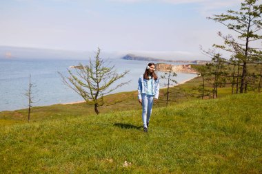 Genç bir kız yazın Baykal Gölü kıyısında kulaklıkla müzik dinler. Olkhon Adası 'nın güzel manzarası. Seyahat kavramı, özgürlük..