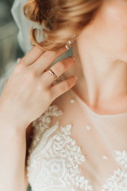 Beyaz gelinlik içindeki genç gelin yüzükle elini gösteriyor.