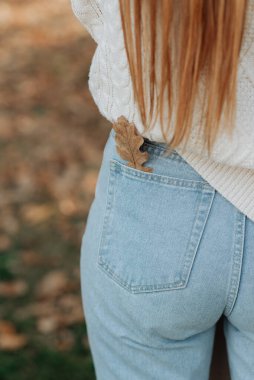 Kotun arka cebinden sarkan güz yaprağı kadın figürü.