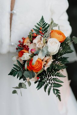 Gelinin ellerinde güzel, parlak bir düğün buketi.