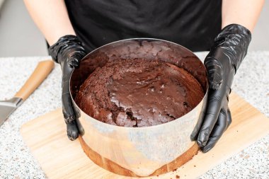 Pasta şefi, aşçı ya da siyah eldivenli fırıncı ve siyah mutfak önlüğü pasta yapıyor. Ev yapımı doğum günü pastası. Ev yapımı hamur işi, kek pişirme, hobi, küçük ev işi.