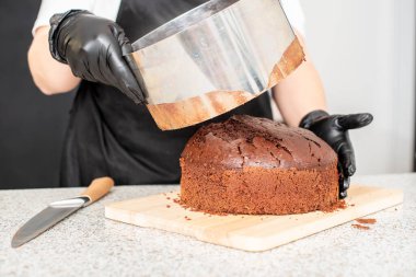 Pasta şefi, aşçı ya da siyah eldivenli fırıncı ve siyah mutfak önlüğü pasta yapıyor. Ev yapımı doğum günü pastası. Ev yapımı hamur işi, kek pişirme, hobi, küçük ev işi.