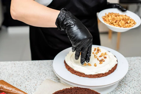 Pastry chef cook confectioner or baker  in black gloves and black kitchen apron   makes a cake. Home made birthday cake. Concept of homemade pastry, cooking cakes, hobby, female small home business