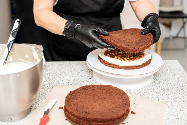 Pastry chef cook confectioner or baker  in black gloves and black kitchen apron   makes a cake. Home made birthday cake. Concept of homemade pastry, cooking cakes, hobby, female small home business