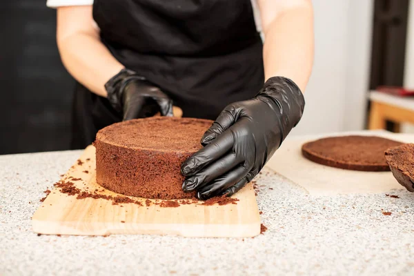 Pastry chef cook confectioner or baker  in black gloves and black kitchen apron   makes a cake. Home made birthday cake. Concept of homemade pastry, cooking cakes, hobby, female small home business