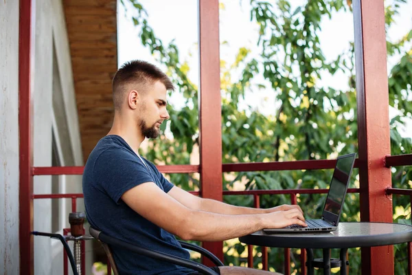 Sakallı genç bir adam dışarıda çalışmak için bilgisayar dizüstü bilgisayar kullanıyor, evde online olarak serbest çalışıyor, yakışıklı bir öğrenci okuyor, öğreniyor, çevrimiçi eğitim alıyor, serbest çalışıyor.