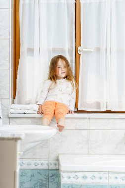 sevimli küçük kız banyo penceresi üzerinde oturan