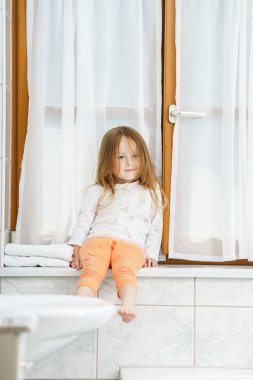 sevimli küçük kız banyo penceresi üzerinde oturan