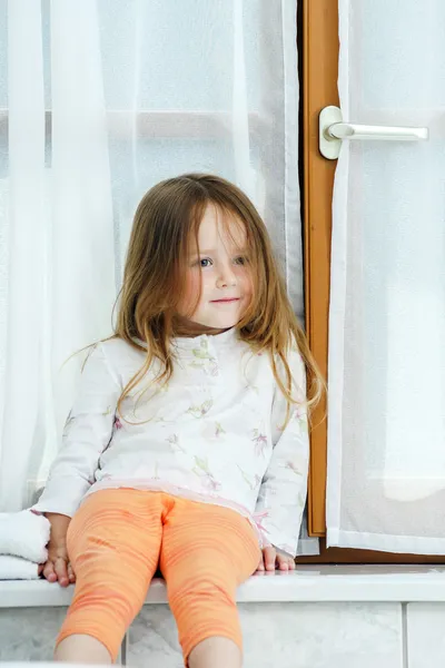 Cute little girl sitting on a bathroom window — Stock Photo, Image