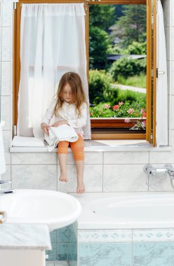 sevimli küçük kız banyo penceresi üzerinde oturan