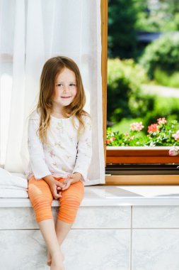 sevimli küçük kız banyo penceresi üzerinde oturan