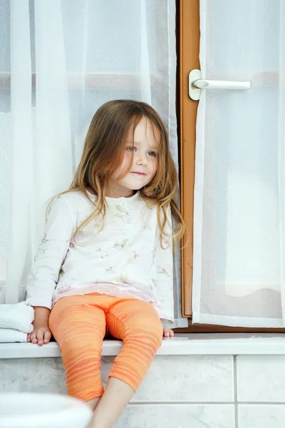 Cute dziewczynka siedzi w oknie łazienki — Zdjęcie stockowe