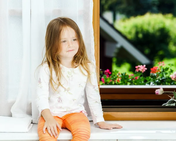 Sevimli küçük kız banyo penceresi üzerinde oturan — Stok fotoğraf