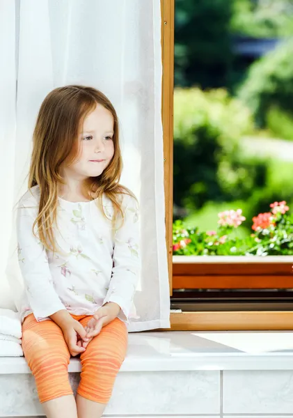 Schattig klein meisje, zittend op een badkamer venster — Stockfoto