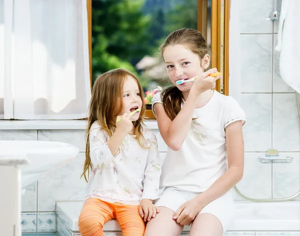 Twee zussen reiniging van de tanden samen — Stockfoto