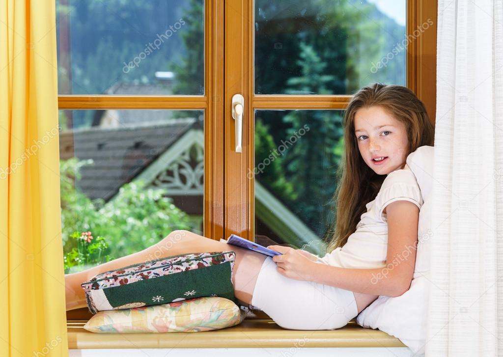 Cute teenage girl siiting on window siil 
