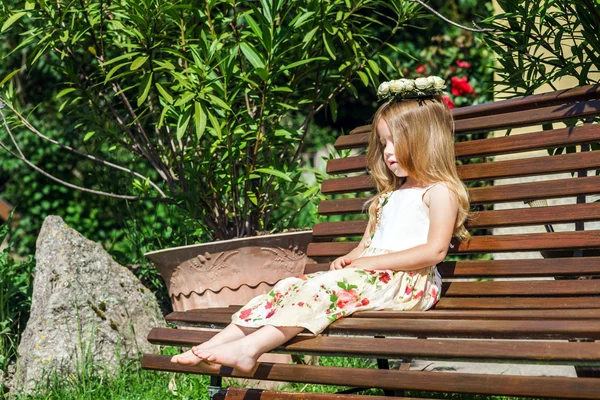 Mignon litle pieds nus fille assise sur le banc — Photo