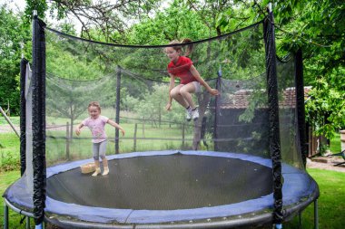Two happy sisters on trampoline clipart