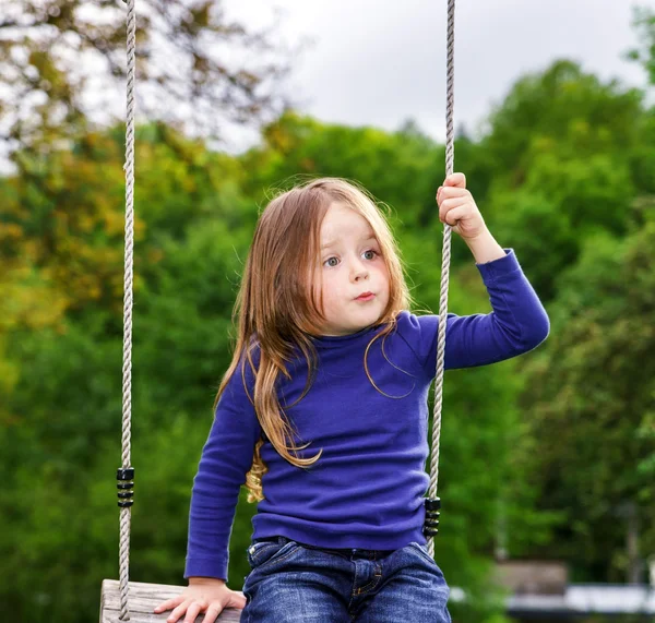 Linda niña balanceándose en el balancín —  Fotos de Stock