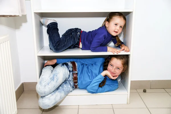 Two sisters fitting in storage rack — Stock Photo, Image