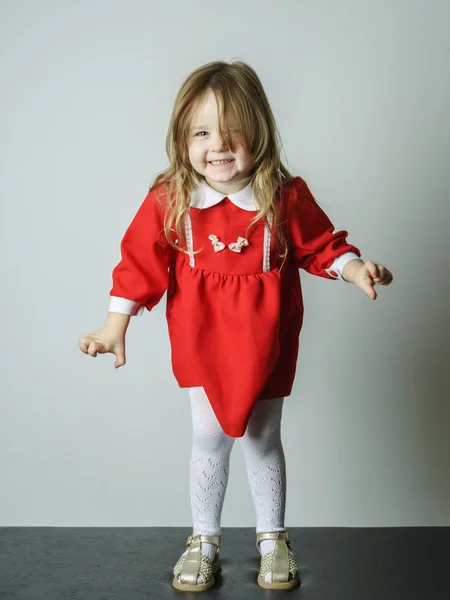 Malá holčička v červených šatech strašit fotograf — Stock fotografie