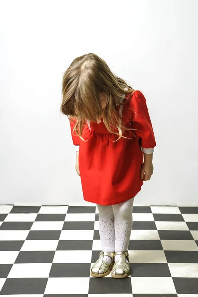 Little girl on checkered floor — Stock Photo, Image