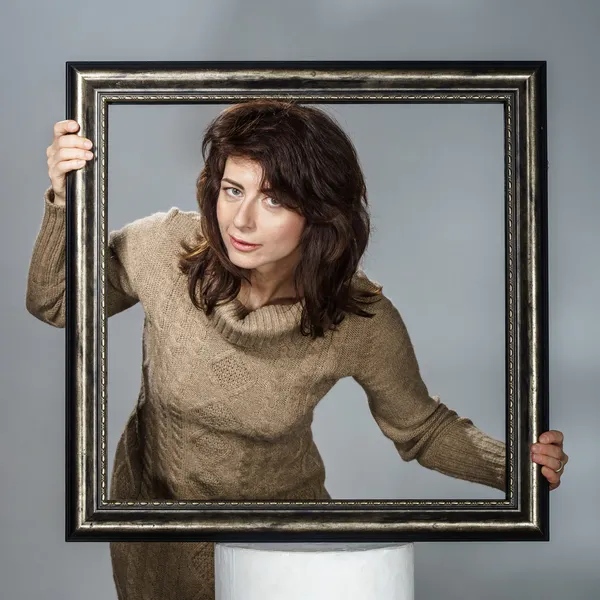 Young woman lean out from picture frame — Stock Photo, Image