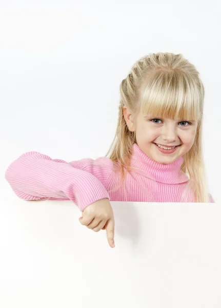 Cute little towhead girl showing to white sheet — Stock Photo, Image