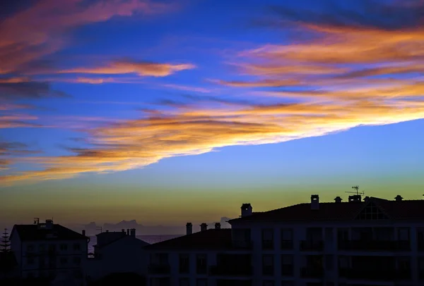 Färgsprakande solnedgång över hus silhuetter — Stockfoto