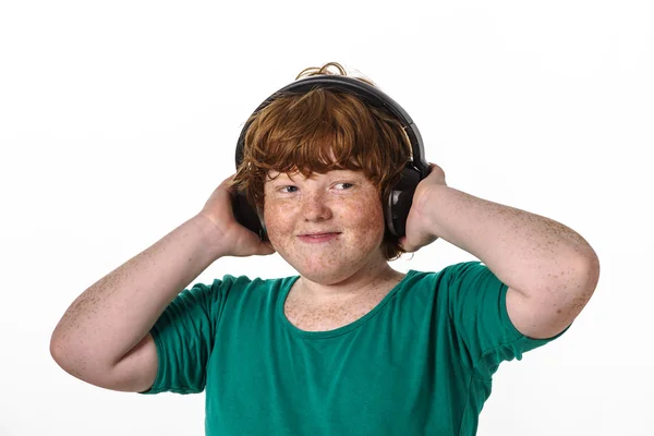 Piegowaty chłopiec czerwony włosy słuchania muzyki. — Zdjęcie stockowe