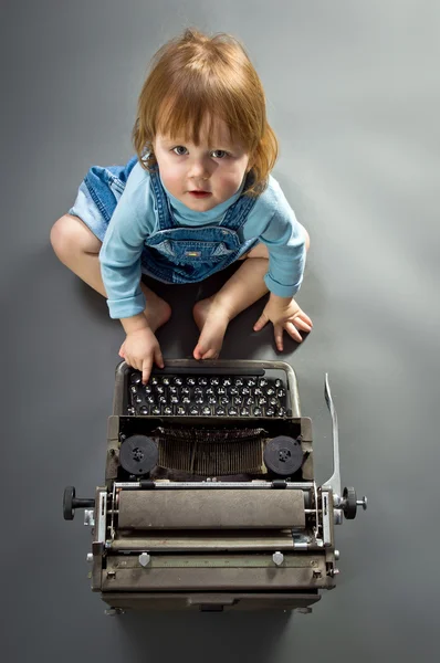 Cute little baby with retro style typewriter — Stock Photo, Image