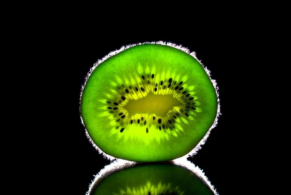 Bright green natural kiwi on black mirror background — Stock Photo, Image