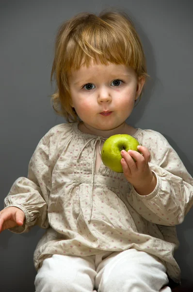 Bayi kecil yang lucu dengan apel hijau dengan latar belakang abu-abu — Stok Foto