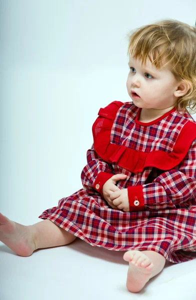 Niedliches kleines Baby im roten Kleid auf weißem Junggesellengrund — Stockfoto